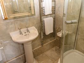 A bathroom with a pedestal sink a mirror towel rack with towels and a glass enclosed corner shower at Pagecroft Cottage in Haydon Bridge