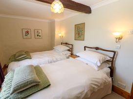 A bedroom with two single beds wooden headboards green cushions and framed floral pictures on the walls at Pagecroft Cottage in Haydon Bridge
