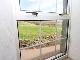 A view of green fields and a stone wall from a white framed window at Pagecroft Cottage in Haydon Bridge