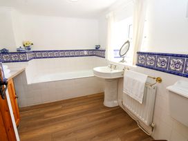 A bathroom with a bathtub sink and toilet with blue patterned tile border on walls at Pagecroft Cottage in Haydon Bridge