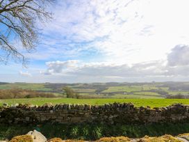 A rural landscape with green fields and rolling hills behind a stone wall at Pagecroft Cottage in Haydon Bridge