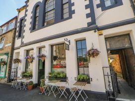 An exterior view of a coffee shop with outdoor tables and hanging flower baskets at Pagecroft Cottage in Haydon Bridge