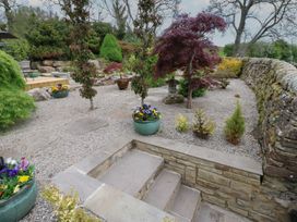 An outdoor garden area with stone steps flower pots trees and shrubs at Pagecroft Cottage in Haydon Bridge