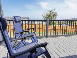 A deck with rocking chairs and a fence at Birch Cottage in Scarborough