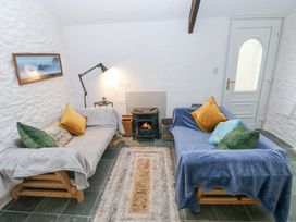 A small sitting room with two sofas facing a wood stove and a lamp on a side table at Anchor Light Castlemartin near Pembroke
