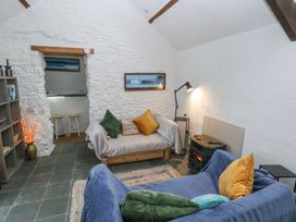 A living room with sofas cushions a floor lamp a wood stove and bookshelf at Anchor Light in Castlemartin near Pembroke