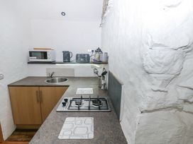 A small kitchen with a gas stove microwave kettle and toaster at Anchor Light Castlemartin near Pembroke