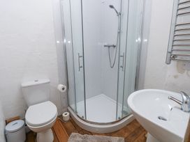 A bathroom with a toilet a shower enclosure and a sink with wooden floor at Anchor Light in Castlemartin near Pembroke