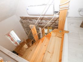 A wooden staircase with rope handrails leading down to a room with stone and plaster walls at Anchor Light Castlemartin near Pembroke