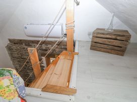 A wooden staircase with rope railing next to a rustic wooden crate with a glass vase in a small attic space at Anchor Light in Castlemartin near Pembroke