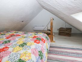 A small attic bedroom with a colorful patchwork quilt on the bed a wooden crate used as a table and light wood flooring at Anchor Light in Castlemartin near Pembroke