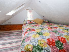 A small attic bedroom with a bed covered in a colorful patchwork quilt at Anchor Light in Castlemartin near Pembroke