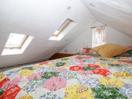 A bedroom with a colorful patchwork quilt on the bed and skylights in a slanted ceiling at Anchor Light in Castlemartin near Pembroke