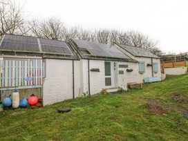 A small stone cottage with solar panels on the roof and grassy yard at Anchor Light in Castlemartin near Pembroke