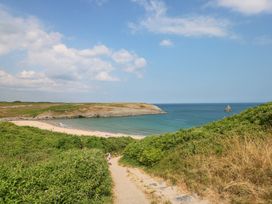 A sandy beach with people and steps leading down through green bushes at Anchor Light in Castlemartin near Pembroke