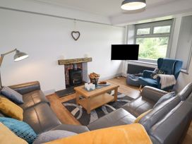 A living room with grey sofas a wooden coffee table a fireplace and a blue armchair at Segrwyd Uchaf in Denbigh near Conwy
