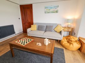A living room with a sofa yellow cushions a wooden coffee table with a checkers game and jenga blocks at Segrwyd Uchaf Denbigh near Conwy