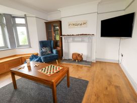 A living room with a blue armchair wooden table with games and a TV on the wall at Segrwyd Uchaf in Denbigh near Conwy