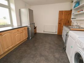A kitchen with wooden cabinets refrigerator washing machine and stainless steel sink at Segrwyd Uchaf in Denbigh near Conwy