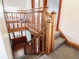 A wooden staircase with decorative balusters and carpeted steps at Segrwyd Uchaf in Denbigh near Conwy