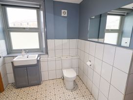 A bathroom with a toilet sink a large mirror and patterned floor tiles at Segrwyd Uchaf in Denbigh near Conwy
