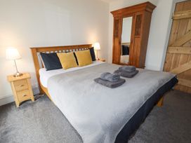 A bedroom with a wooden bed and bedside tables with lamps and a wooden wardrobe with a mirror at Segrwyd Uchaf in Denbigh near Conwy