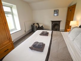 A bedroom with a bed folded towels an armchair a fireplace a window and wooden furniture at Segrwyd Uchaf in Denbigh near Conwy