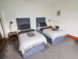 A bedroom with two single beds bedside tables and lamps at Segrwyd Uchaf in Denbigh near Conwy