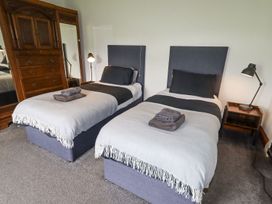 A bedroom with two single beds side by side with grey headboards and white and black bedding at Segrwyd Uchaf in Denbigh near Conwy