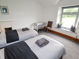 A bedroom with two single beds a small desk and chair and a window seat with cushions at Segrwyd Uchaf in Denbigh near Conwy
