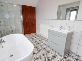 A bathroom with a freestanding bathtub shower enclosure vanity unit and wooden door at Segrwyd Uchaf in Denbigh near Conwy