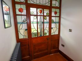 A wooden door with stained glass panels featuring floral designs in a hallway at Segrwyd Uchaf in Denbigh near Conwy