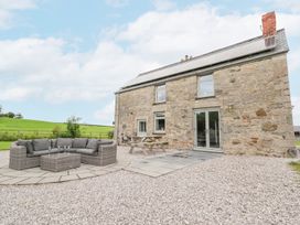 A stone house with solar panels on the roof outdoor seating area and picnic table on gravel at Segrwyd Uchaf in Denbigh near Conwy