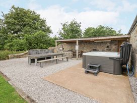 An outdoor area with a hot tub and picnic table near stone walls at Segrwyd Uchaf in Denbigh near Conwy