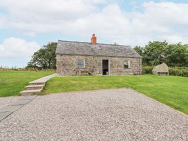 A stone cottage with a tiled roof and chimney surrounded by grass and gravel at Segrwyd Uchaf in Denbigh near Conwy