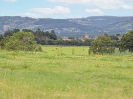 A grassy field with trees and hills in the background at Segrwyd Uchaf in Denbigh near Conwy