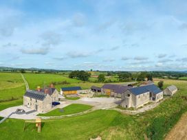 A farmhouse with outbuildings and green fields in the countryside at Segrwyd Uchaf in Denbigh near Conwy