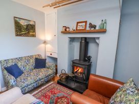 A sitting room with a wood burning stove two sofas a painting on the wall and a rug on the floor at Whinstone Cottage in Esk Valley near Grosmont