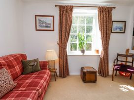 A sitting room with a red plaid sofa cushions a lamp and framed pictures at Whinstone Cottage Esk Valley near Grosmont