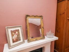 A mantelpiece with a framed picture a decorative mirror and a glass container at Whinstone Cottage Esk Valley near Grosmont