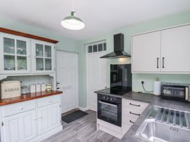 A kitchen with cabinets, oven, sink, and microwave at Whinstone Cottage in Esk Valley near Grosmont