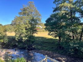 A view of trees and a river in a field at 2 Whinstone Cottage Esk Valley near Grosmont