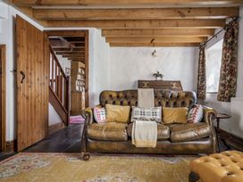 A living room with a sofa and wooden stairs at Cove Cottage Llangrannog