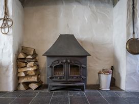 A living room with a wood stove and firewood at Cove Cottage in Llangrannog
