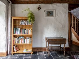 A snug with a bookshelf and a table at Cove Cottage in Llangrannog