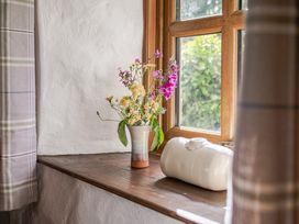 A window with a vase of flowers on a wooden ledge at Cove Cottage Llangrannog