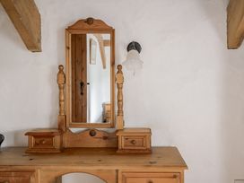 A wooden dresser with a mirror and lamp at Cove Cottage Llangrannog