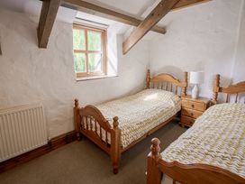 A bedroom with two beds and a window at Cove Cottage in Llangrannog