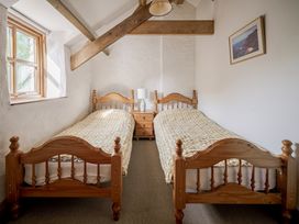 A bedroom with two single beds and a bedside table at Cove Cottage in Llangrannog
