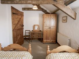 A bedroom with two beds and wooden furniture at Cove Cottage in Llangrannog